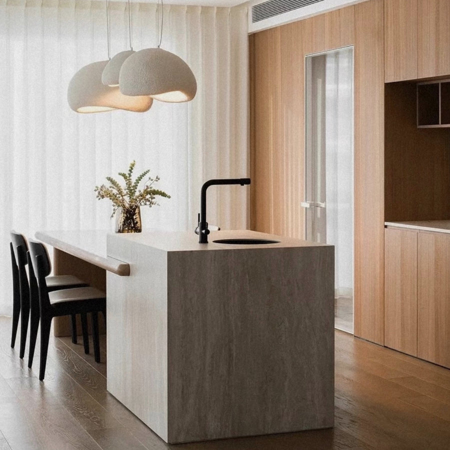 pendant light positioned over a kitchen island with seating in a contemporary interior.