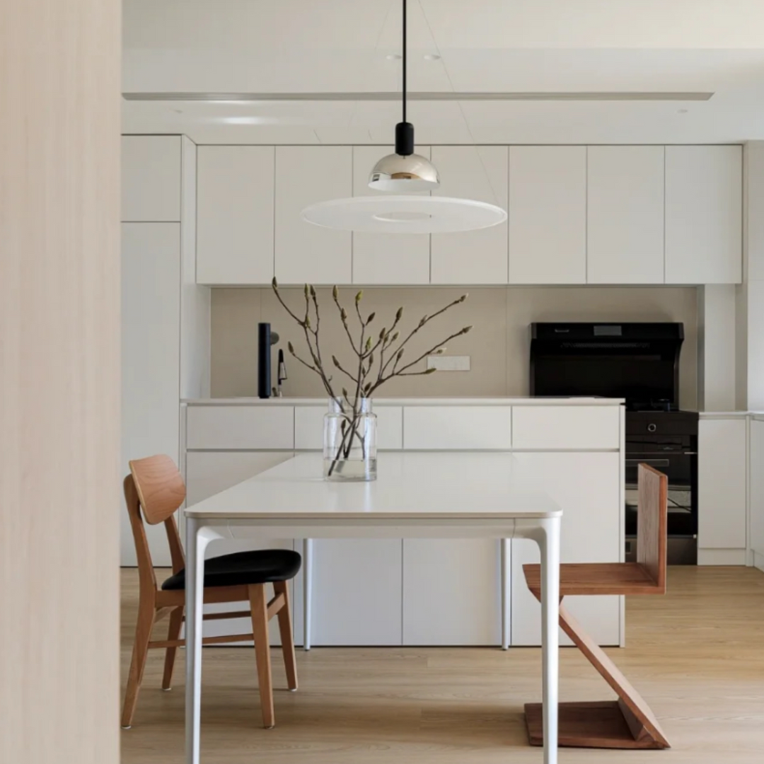 Light-filled modern kitchen with chrome pendant light and white table