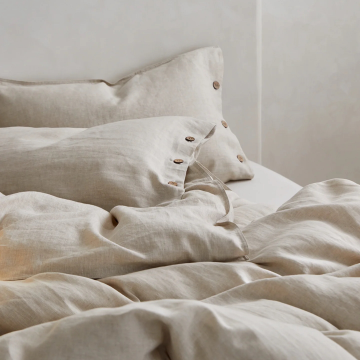 Linen pillowcase featuring wooden buttons, highlighting the detailed craftsmanship and rustic charm of this premium linen bedding accessory