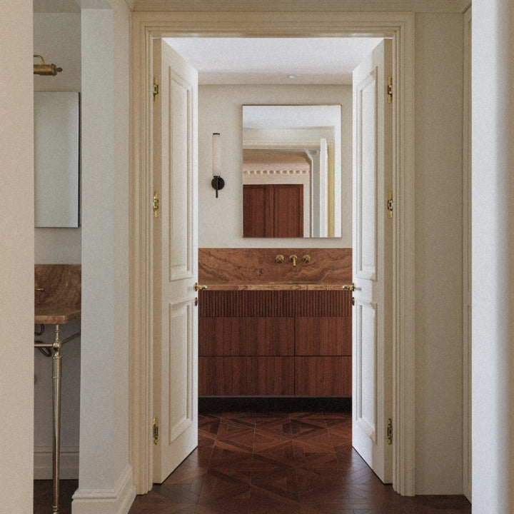 luxury marble wall light installed along a hallway leading to a bathroom with warm interior lighting.