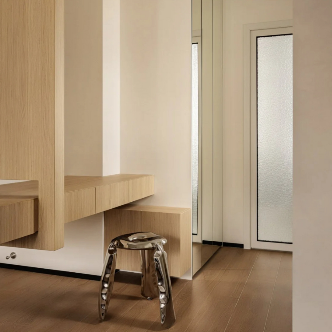 Modern metal stool in a clean and minimalist hallway setting.