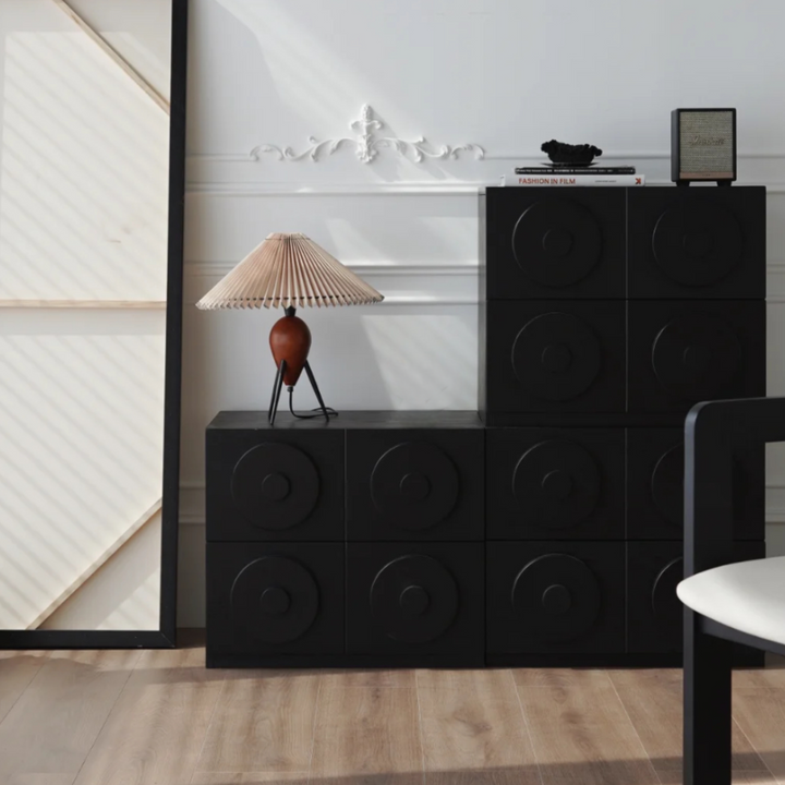 Mid-century modern lamp on a black dresser in a minimalist room setting.