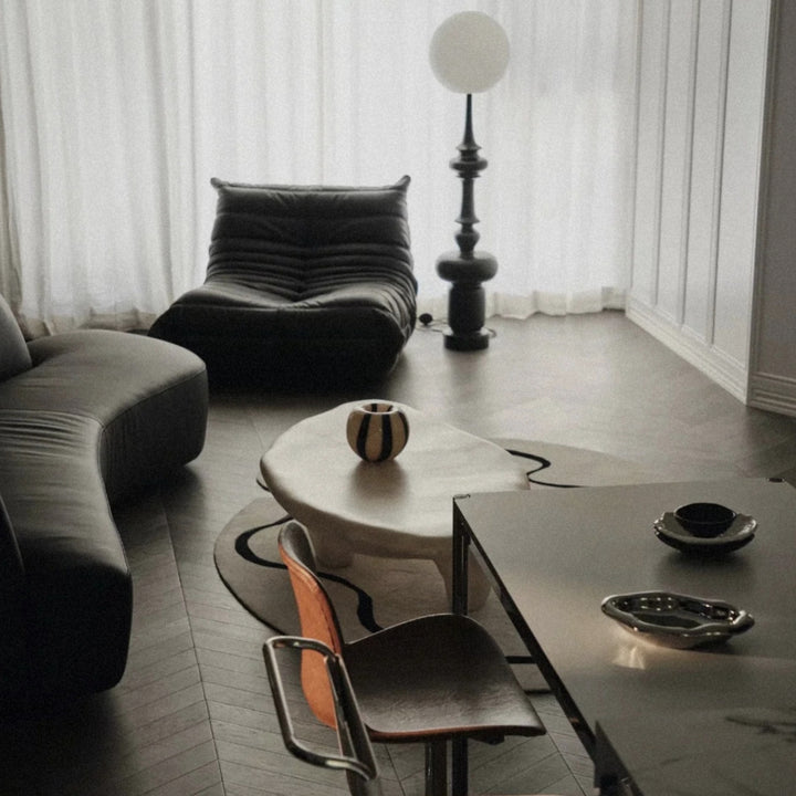 in a modern lounge interior a small glass vase sits on a coffee table beside seating.