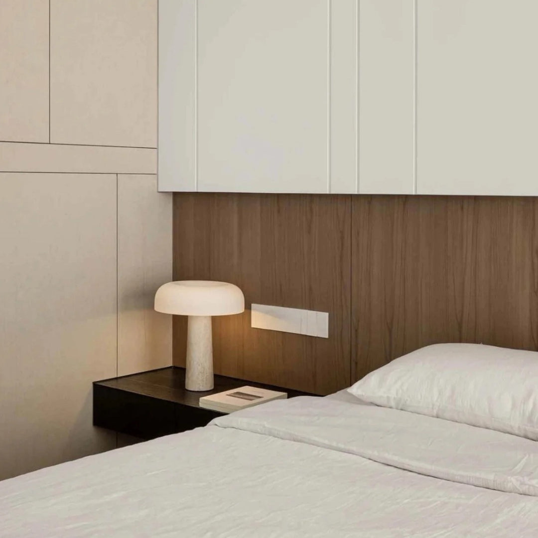 minimal modern table lamp with a stone base placed on a bedside table in a neutral bedroom interior.
