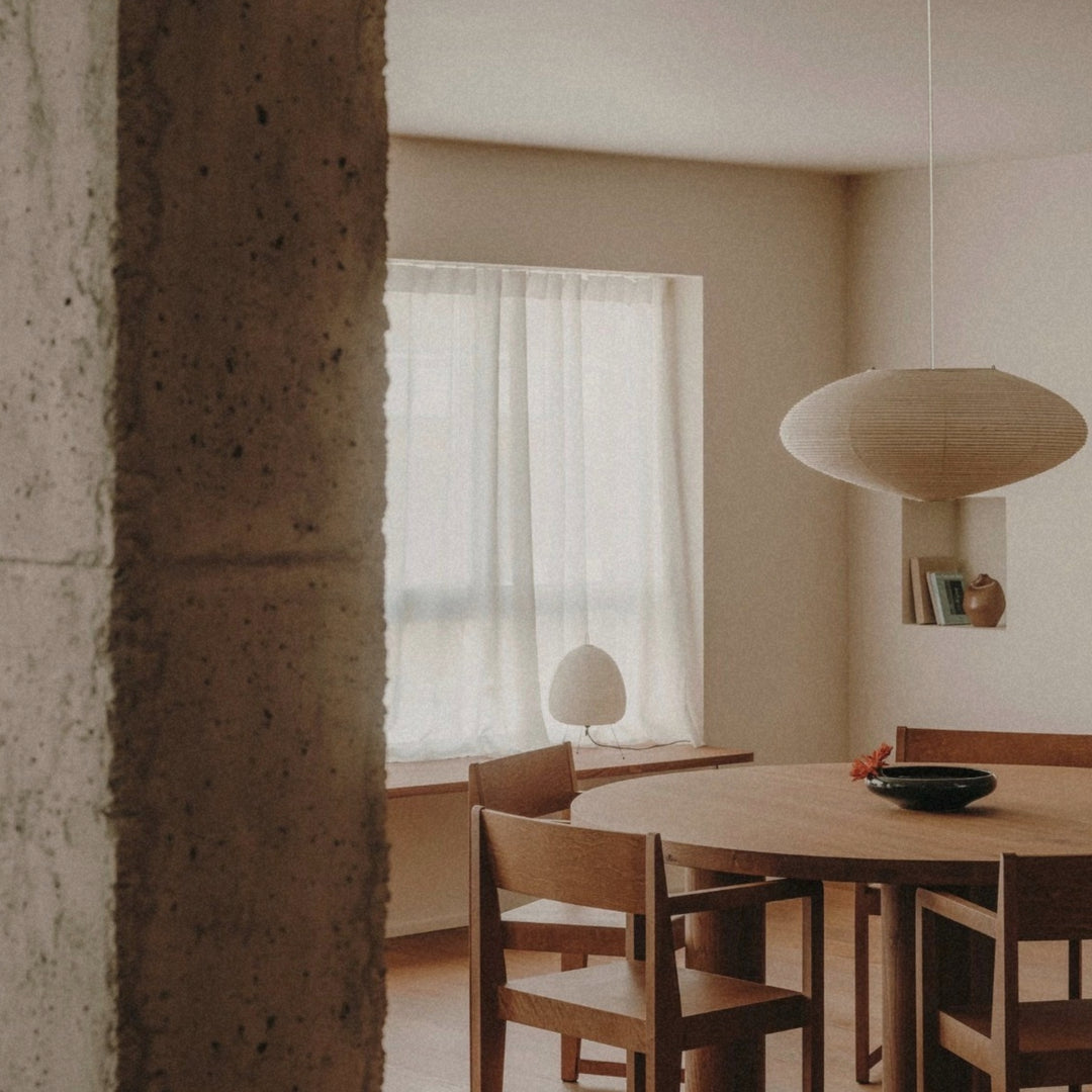 minimal paper pendant light hanging above a small dining table near a window.