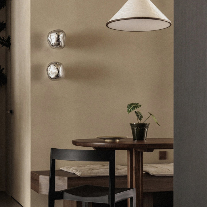 minimal wall sconce with glass finish placed beside a dining table.
