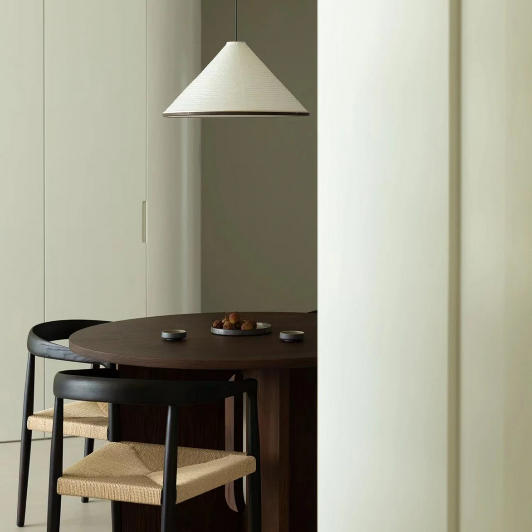 Elegant cotton paper pendant light placed above a wooden dining table in a clean, minimalist space.