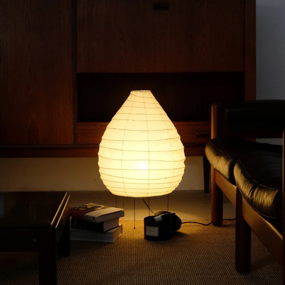 Minimalist floor lamp glowing next to a vintage console in a Japandi-inspired neutral-toned lounge.