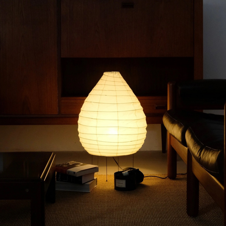 Minimalist floor lamp glowing next to a vintage console in a Japandi-inspired neutral-toned lounge.