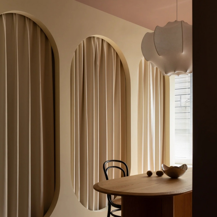 Minimalist pendant lamp in a serene room setting, perfectly complementing the soft curves of the window treatments.