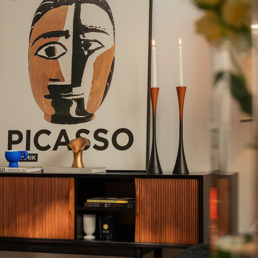 Two wooden candle holders styled with neutral-toned books and a ceramic vase in an organic interior.