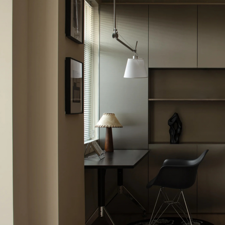 Contemporary home office with dark wood desk, ergonomic chair, and warm table lamp