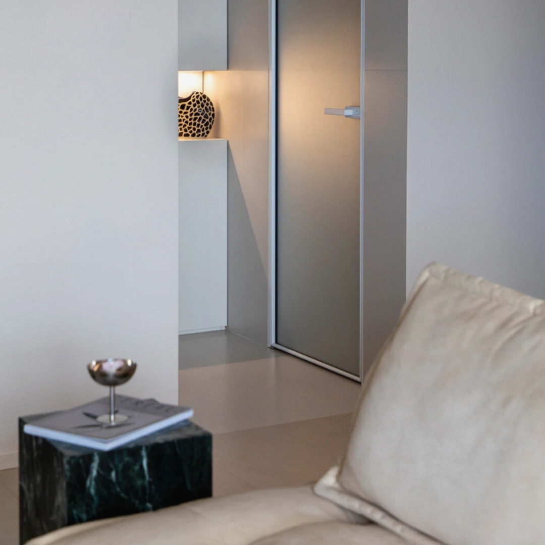 Minimalist marble side table featuring a modern stainless steel coupe, adding elegance to the neutral-toned interior.