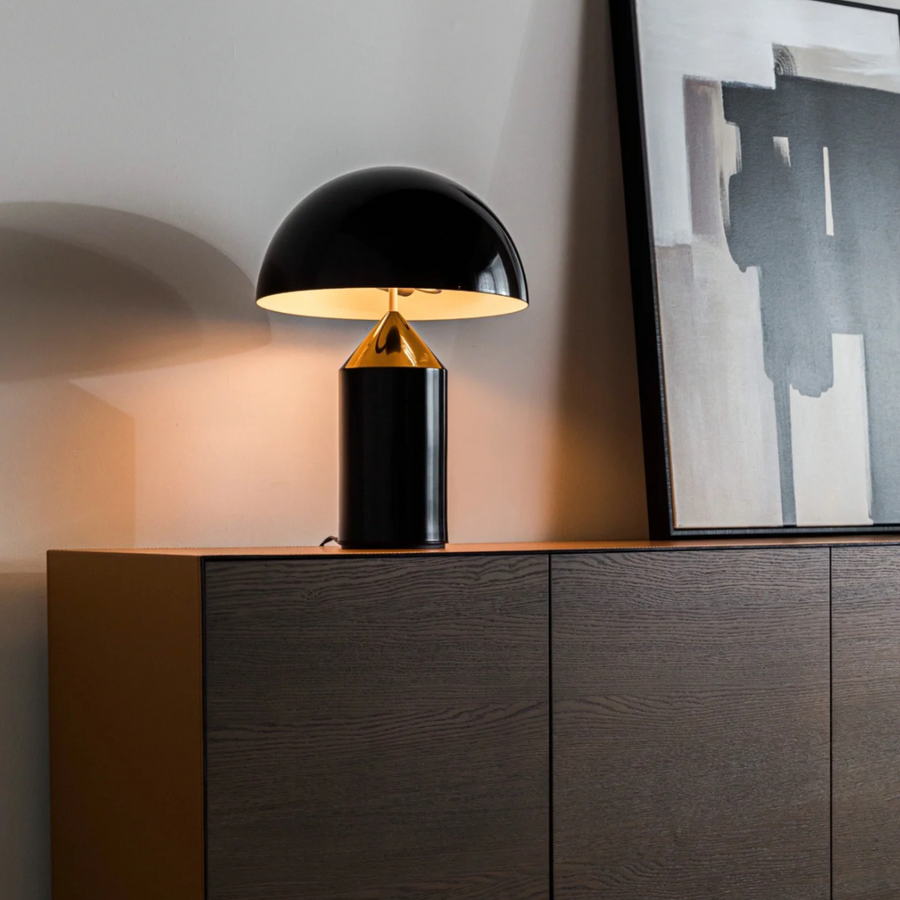 Minimalist table lamp with a bold black dome shade, enhancing the modern aesthetic of a dark-themed room.