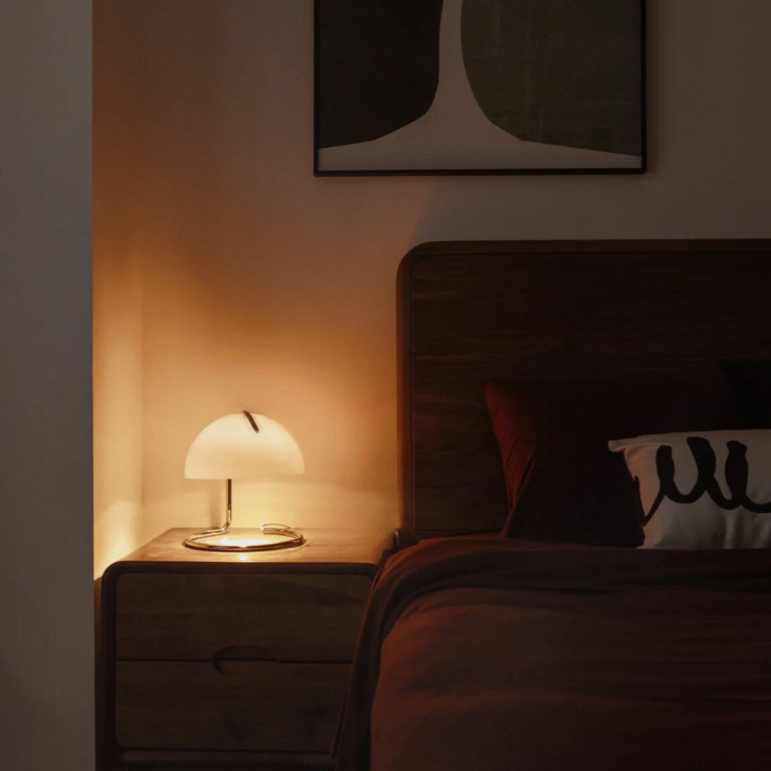 Sleek bedside lamp radiating a warm glow, complementing a cozy wooden nightstand in a stylish bedroom.