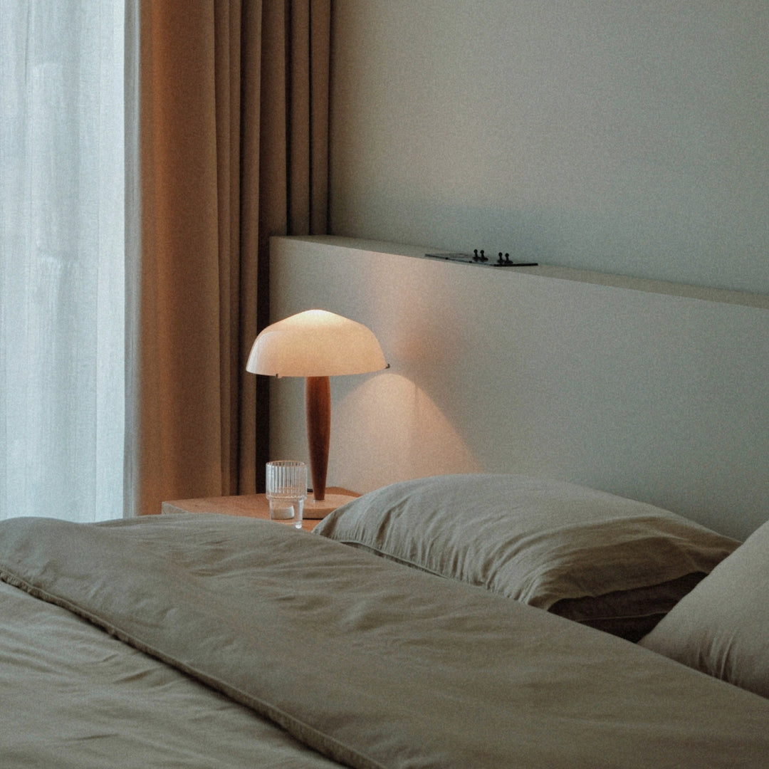 beside the bed a modern table lamp with a smooth glass shade provides gentle lighting.