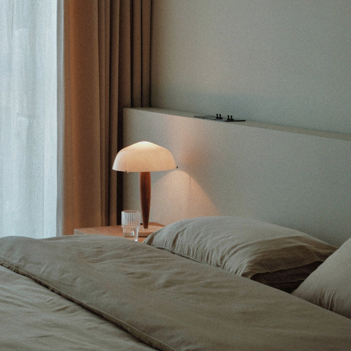 beside the bed a modern table lamp with a smooth glass shade provides gentle lighting.