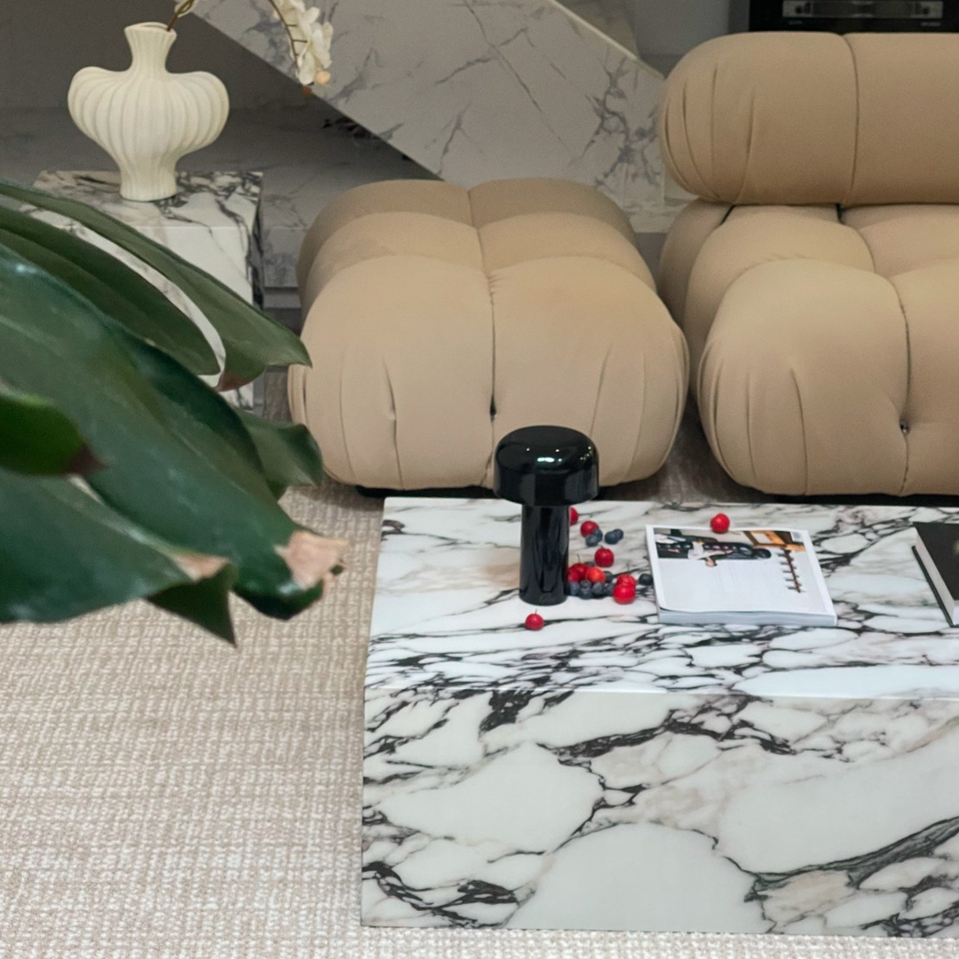 A cordless black mushroom lamp styled with red berries and a design book on a marble coffee table, surrounded by contemporary furniture.