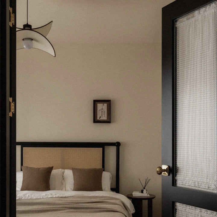 modern ceiling pendant light centered above a bed in a neutral interior.