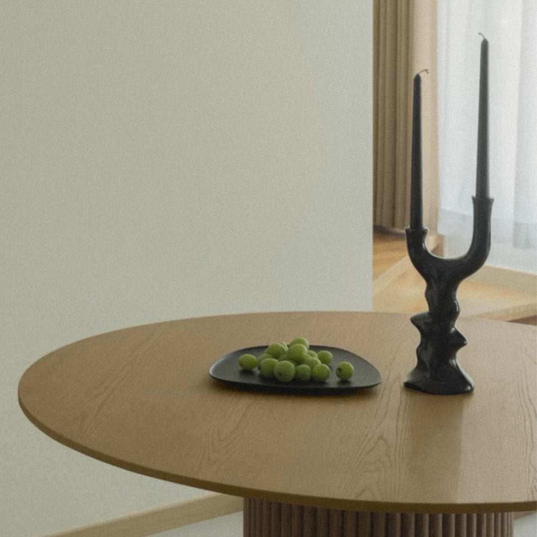 modern ceramic candlestick used as a centerpiece on a round wooden table.