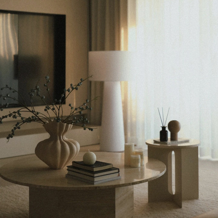 modern decorative ceramic vase with branches styled on a round table in a minimalist japandi interior.