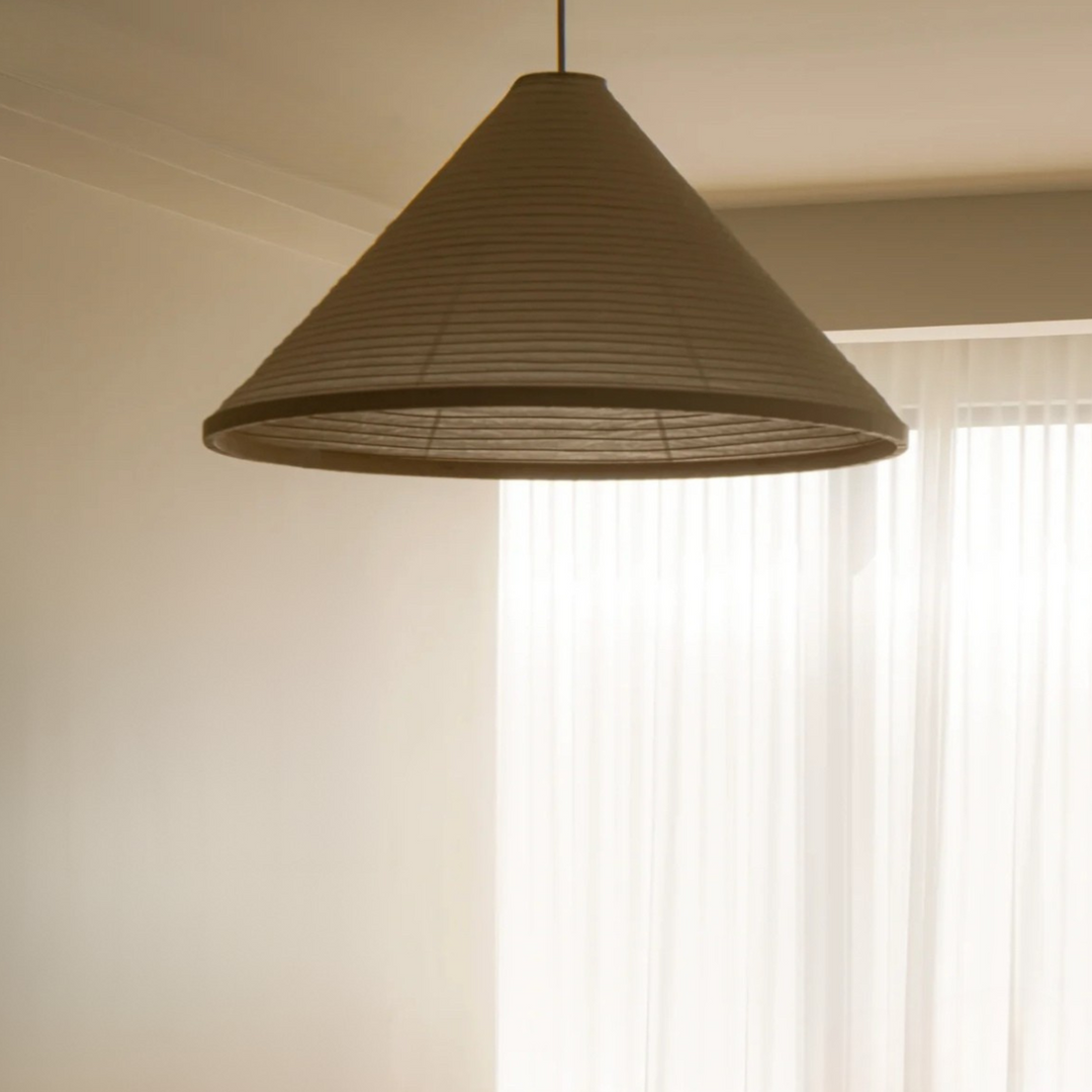 Cotton paper pendant lamp suspended over a wooden dining table in a contemporary dining room.