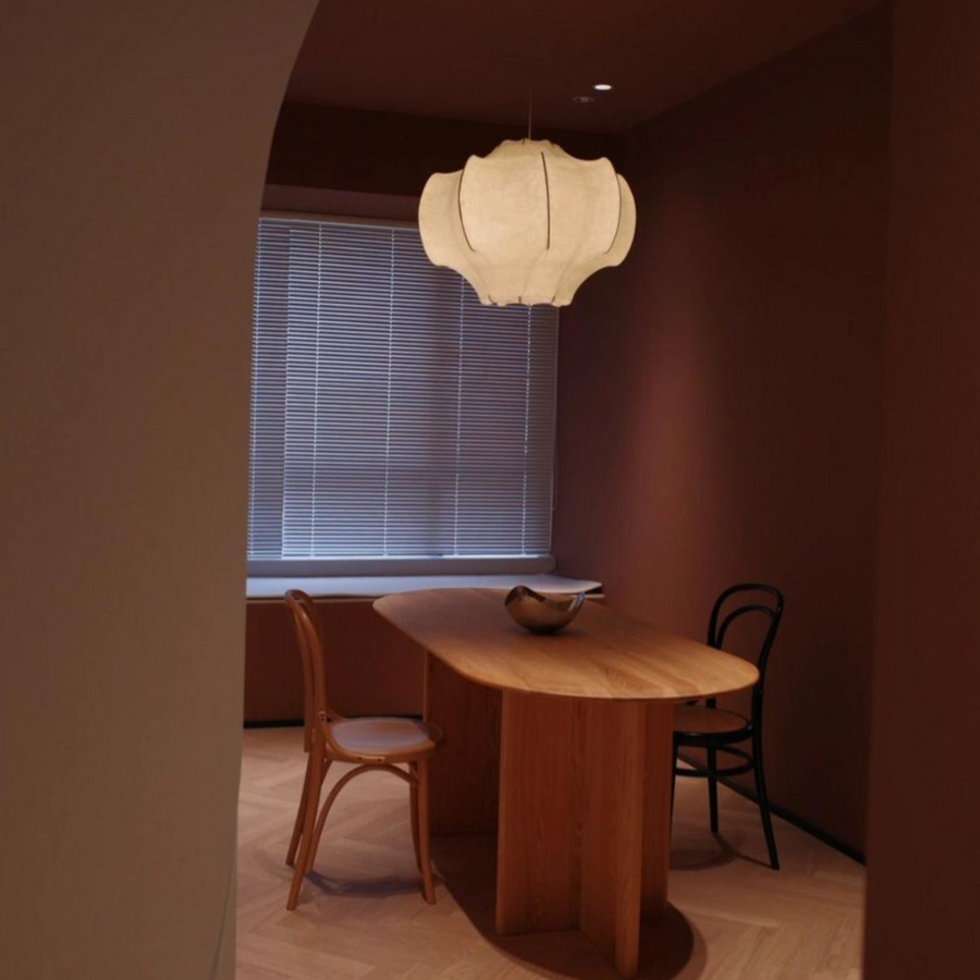 Elegant pendant light hanging above a wooden dining table in a contemporary apartment with neutral tones.