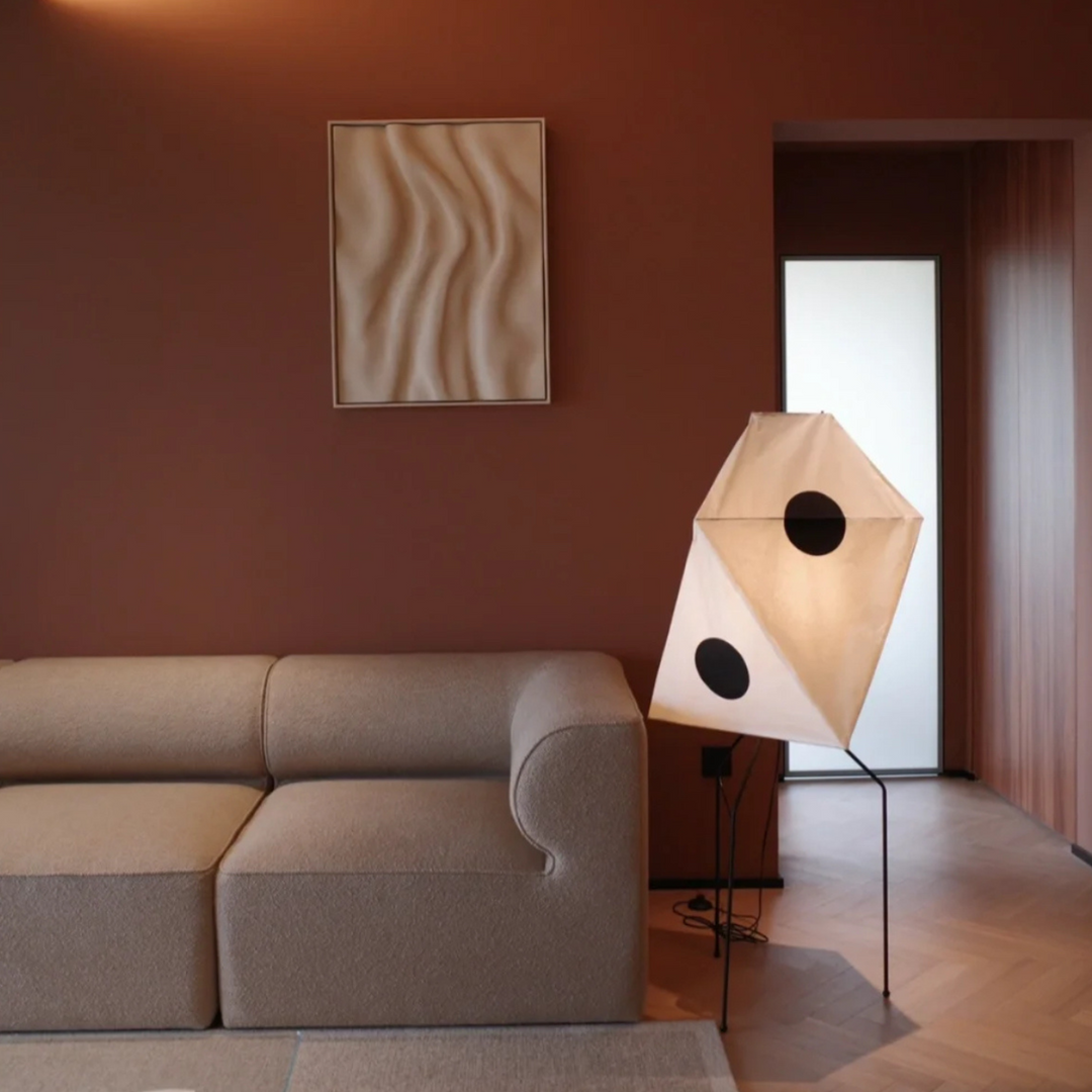 This sculptural cotton paper lamp creates a cozy atmosphere in a modern, neutral-toned living room.