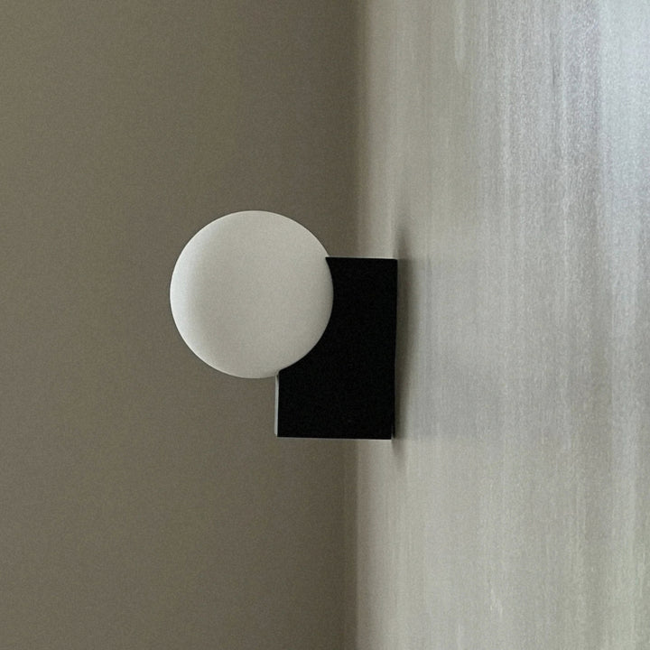round glass wall light fixed to the wall with a clean minimal metal base.
