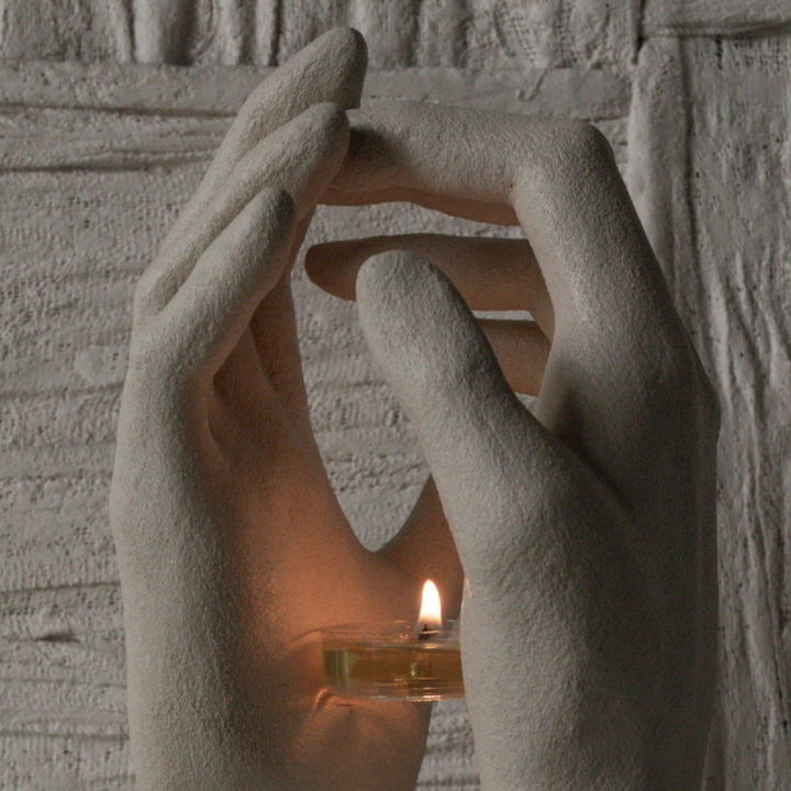 Close-up of sculptural candle holder shaped like holding hands