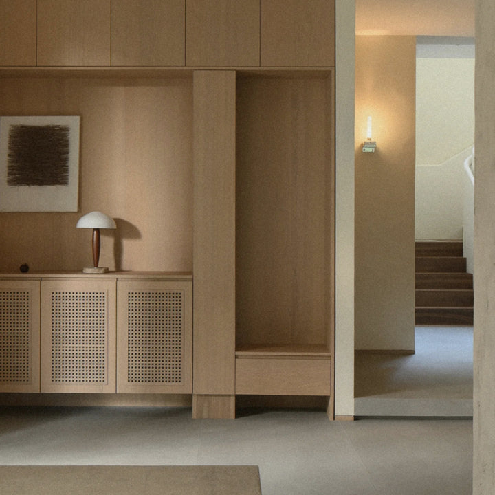 set on a cabinet in a contemporary hallway a marble and glass table lamp brings subtle ambient light.