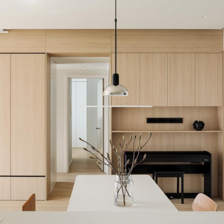 Modern kitchen with chrome pendant light, sleek wood cabinetry, and minimalist white table