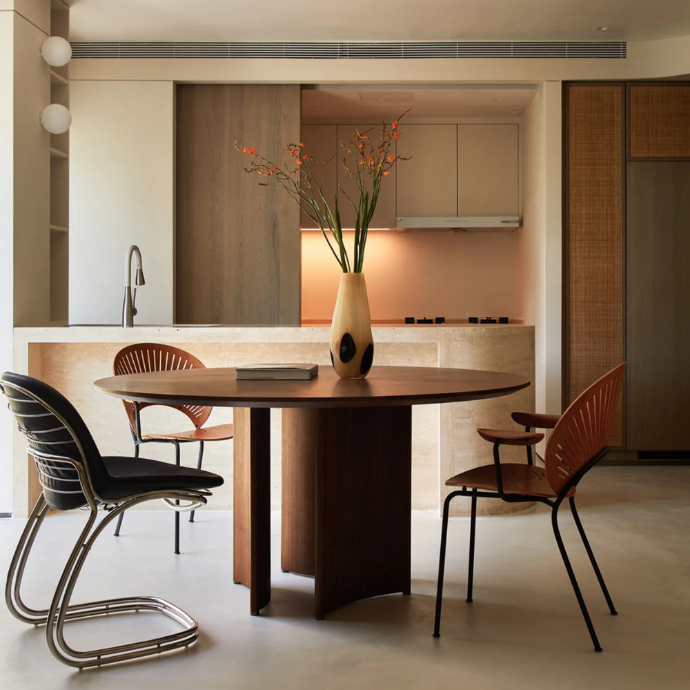 Modern kitchen dining area with stylish vase on a circular table, complemented by unique metal chairs.