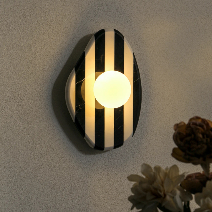 Modern black and white marble wall light illuminated, casting a warm glow with artistic stripes.