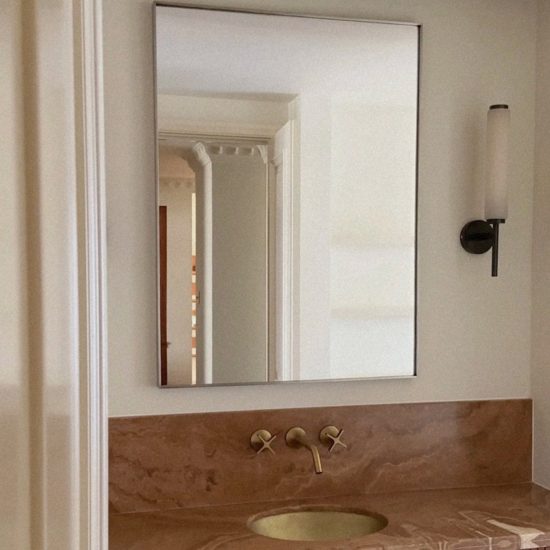 modern marble wall sconce placed beside a mirror providing warm lighting above a bathroom vanity.