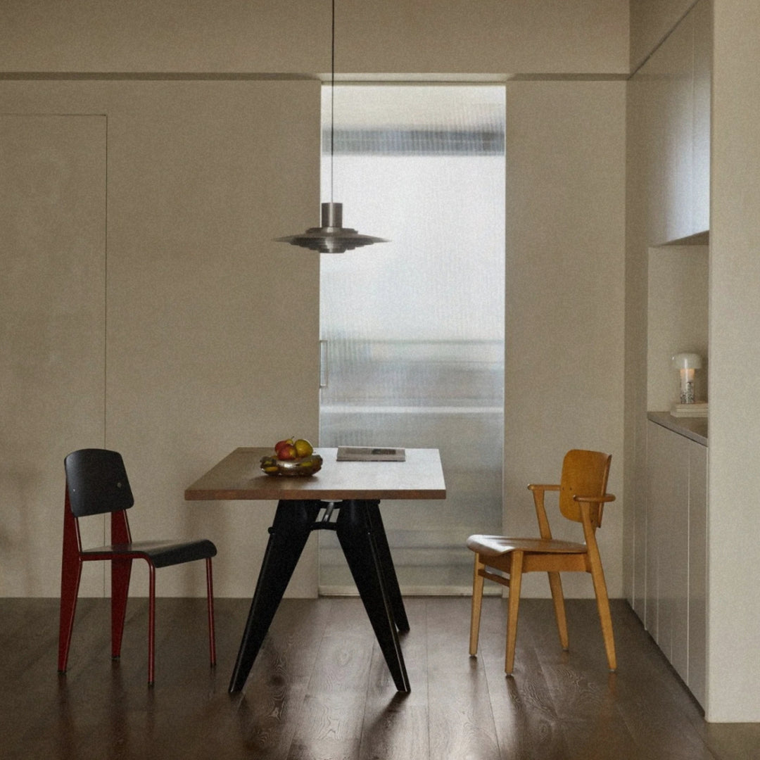 modern metal hanging lamp placed over a dining area with mixed chairs.