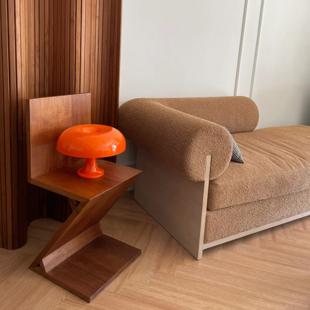 Modern orange table lamp on a unique wooden side table, complementing the cozy, textured couch in a living room.