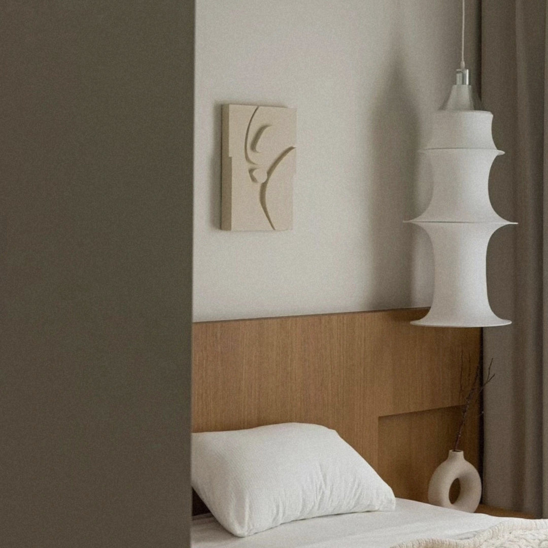 modern pendant light hanging beside a bed creating soft ambient lighting in a bedroom.