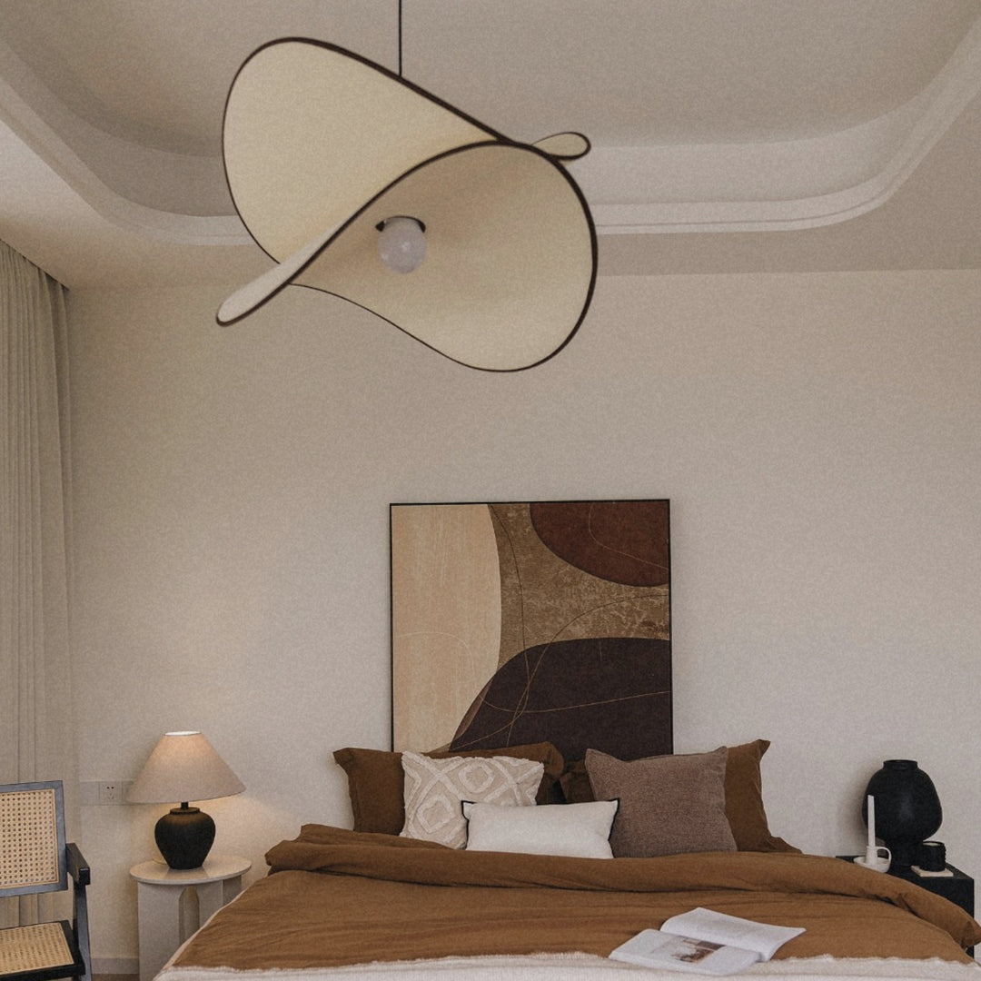 modern pendant light suspended above a bed in a calm bedroom setting.