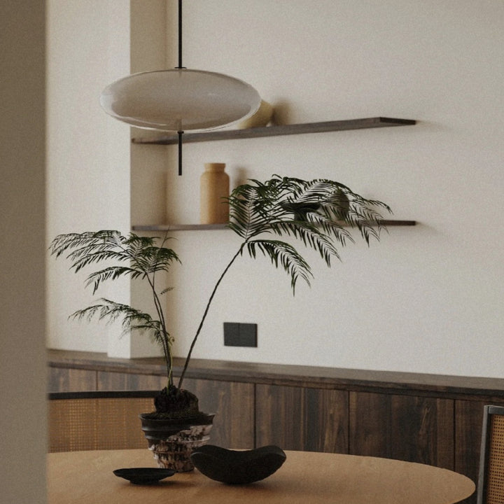 modern pendant light hanging above a dining table in a warm interior.