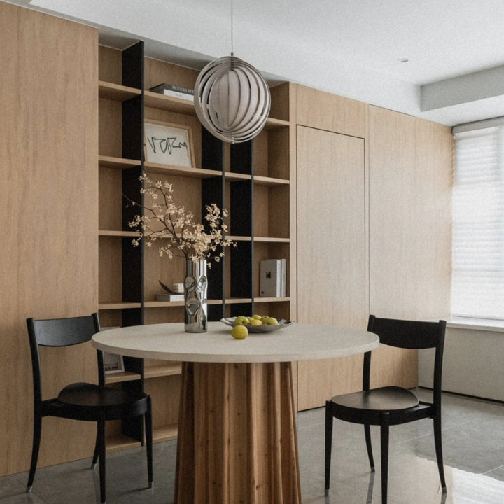 modern pendant light centered above a dining table surrounded by wooden shelving.