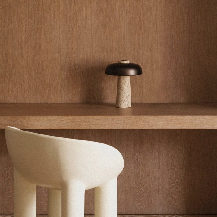 modern stone table lamp sitting on a wooden shelf in a calm interior setting.