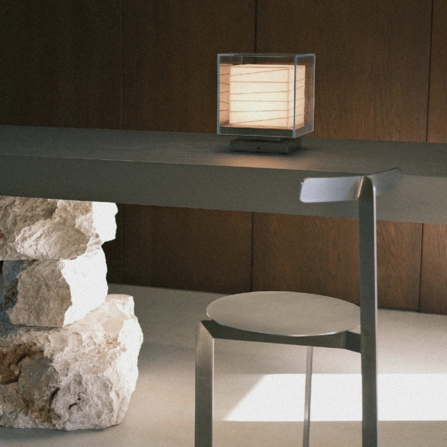 modern table lamp in glass cube form set on a desk in a calm interior.