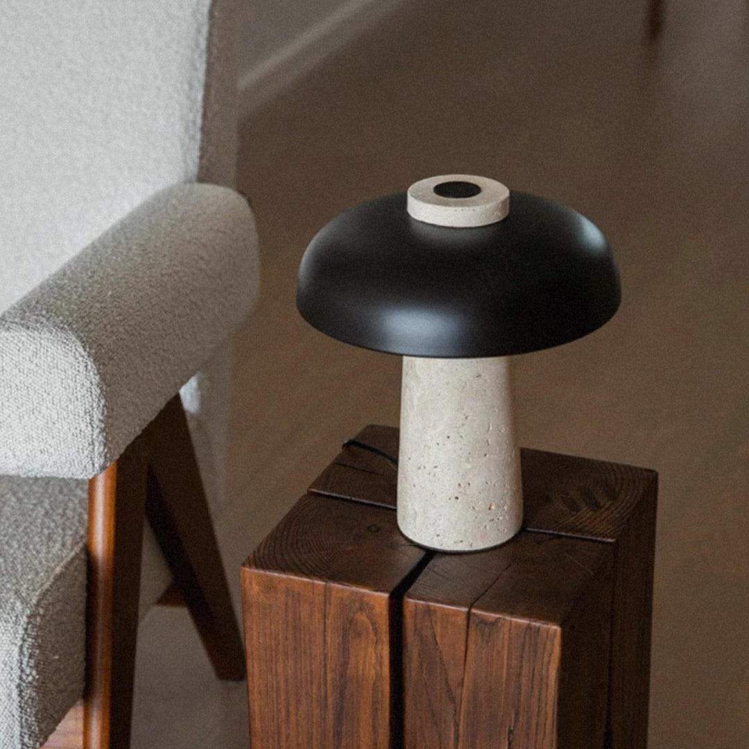 modern table lamp with a travertine base placed on a compact side table next to upholstered seating.