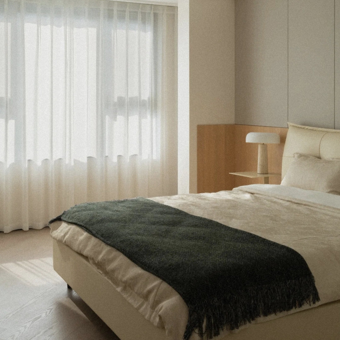 modern travertine table lamp providing soft accent lighting next to a bed in a bright contemporary bedroom.