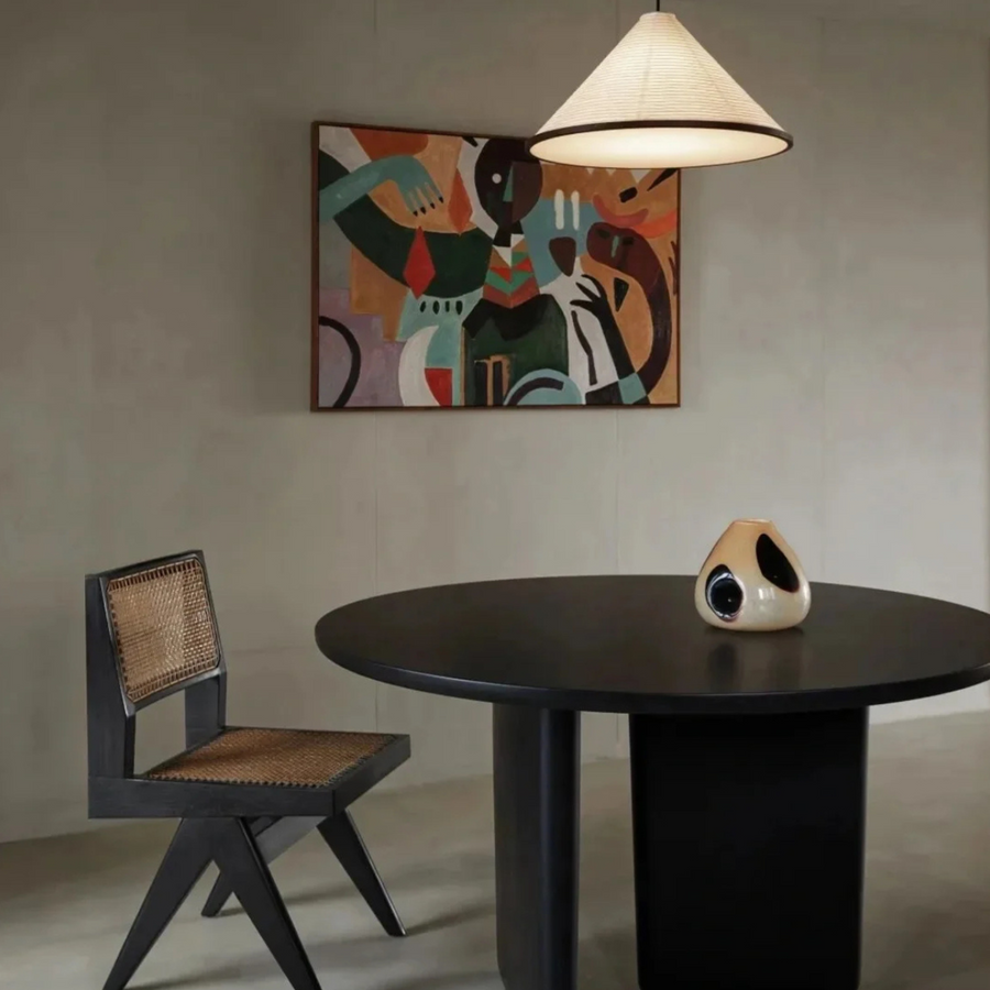 Modern vase on a black dining table complemented by vibrant wall art in a minimalist room.