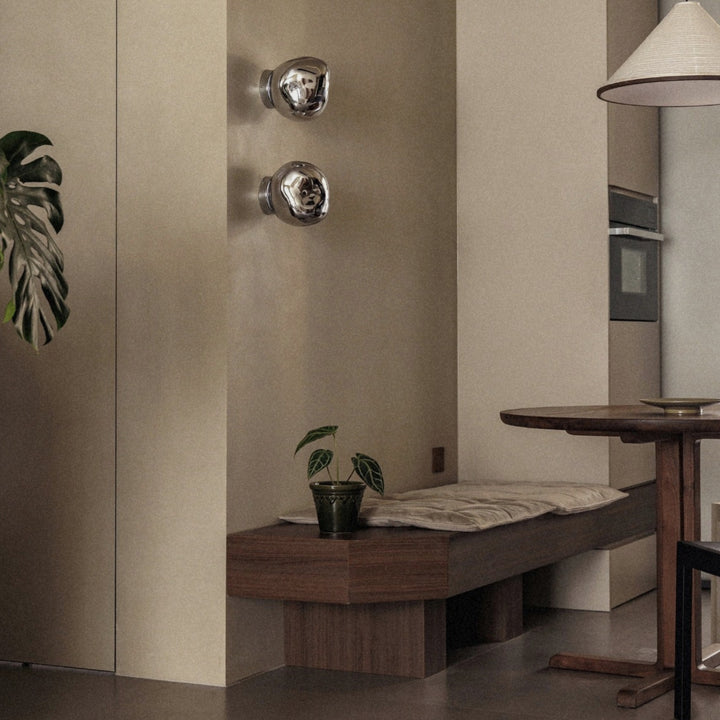 modern wall lamp with glass shade mounted above a wooden bench.