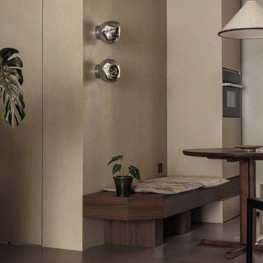 modern wall lamp with glass shade mounted above a wooden bench.