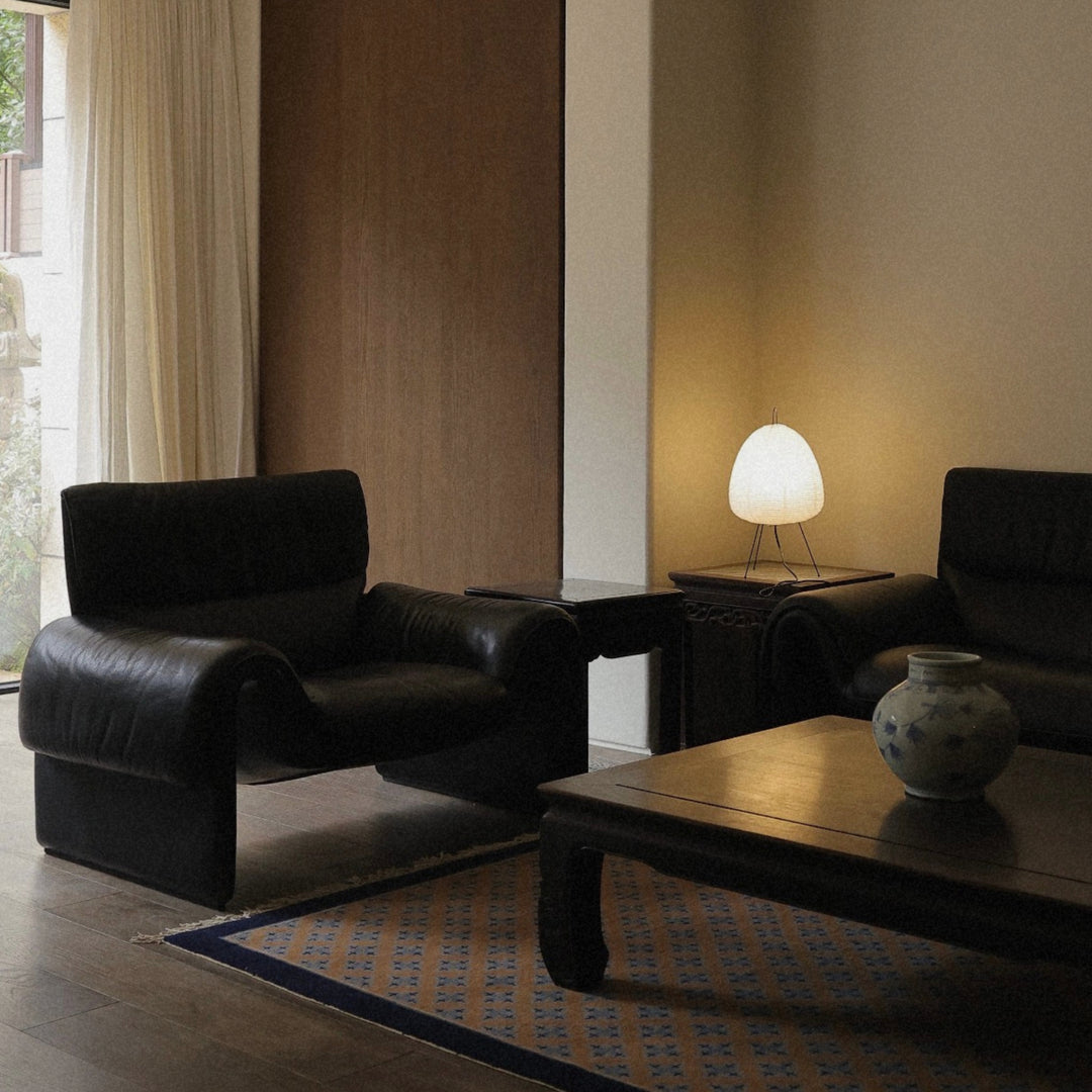 washi paper lamp resting on a low table next to lounge seating in a warm interior.