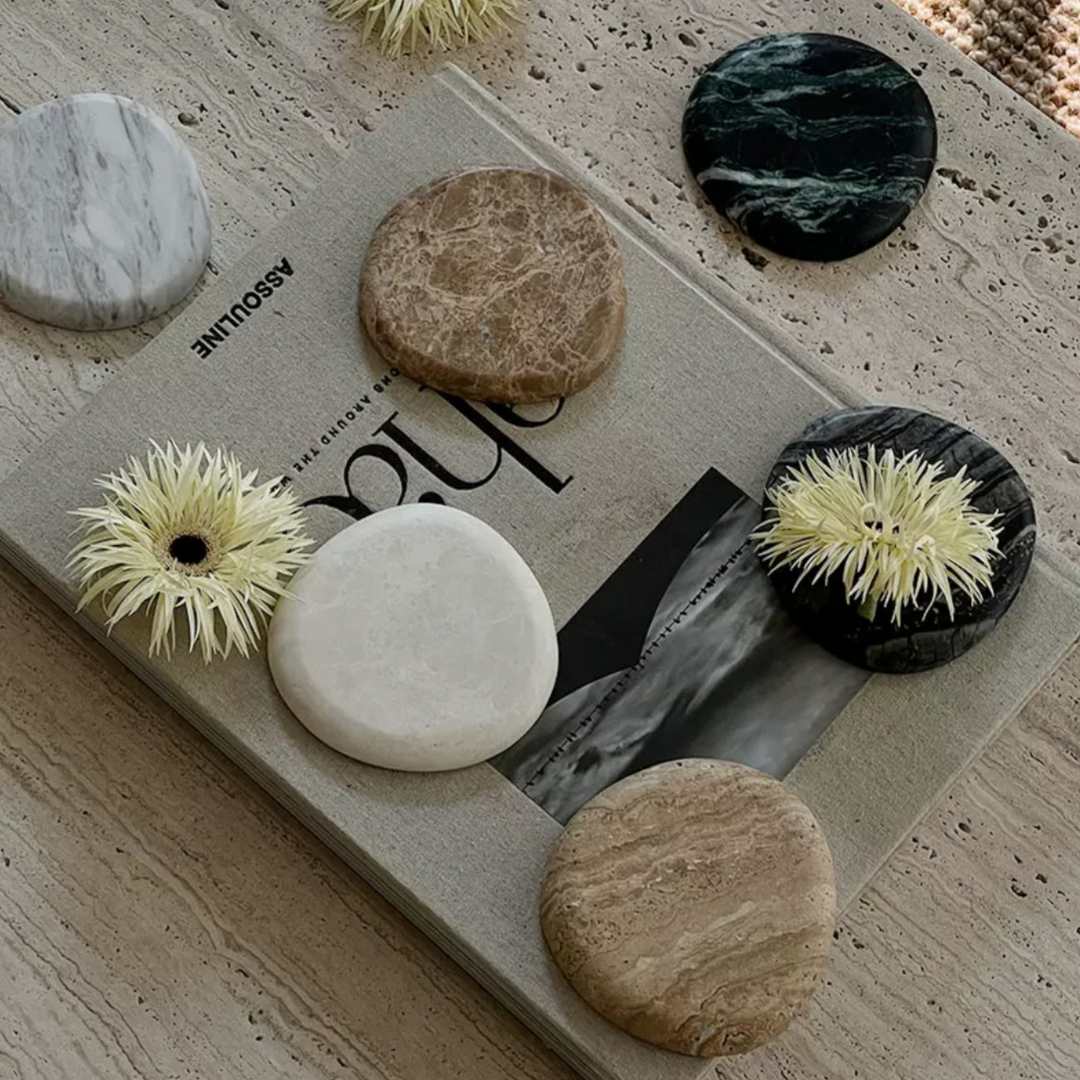 Assorted multi-texture marble coasters on a stylish magazine, perfect for contemporary homes.